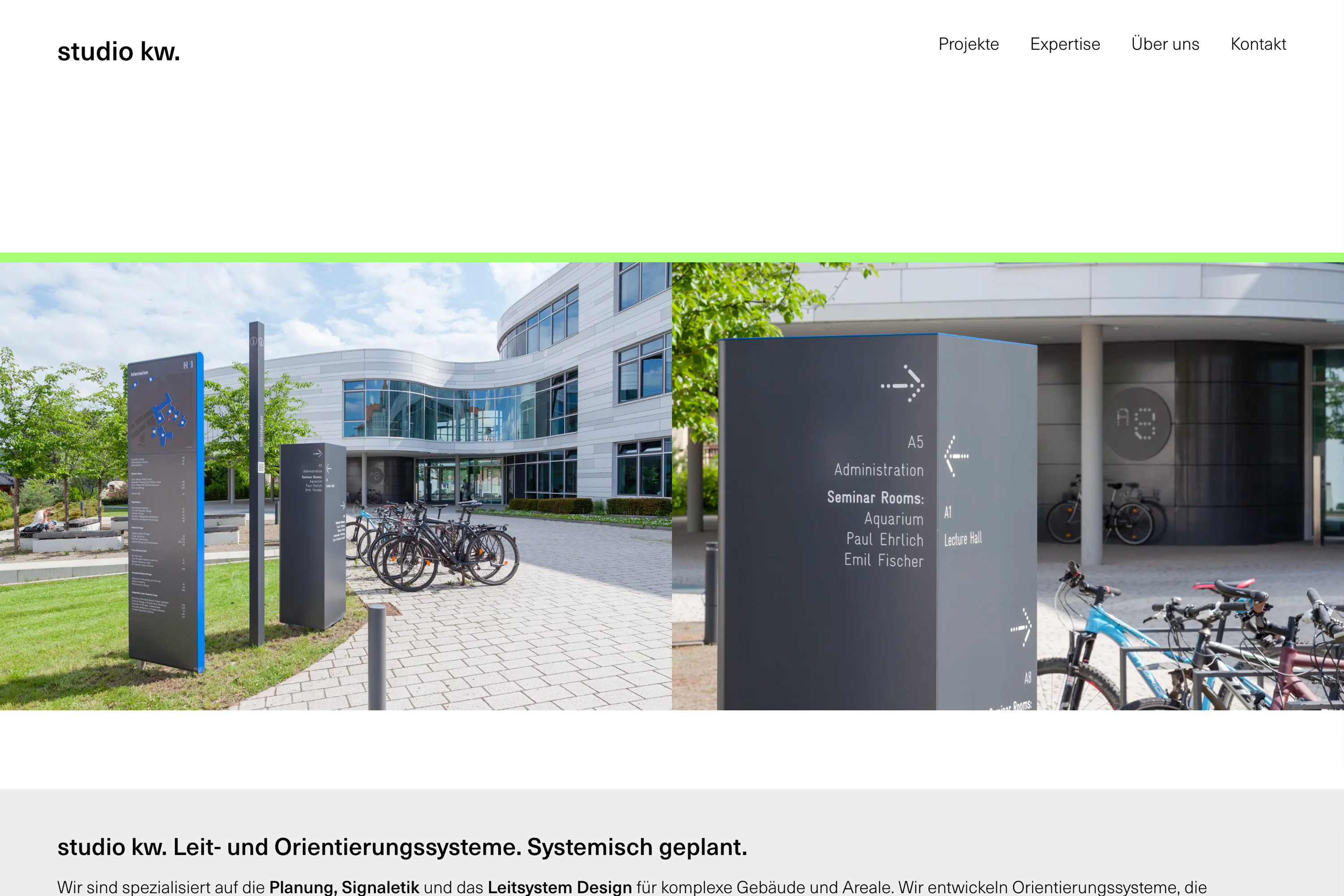 Moderne Gebäude mit Wegweisern im Außenbereich, Fahrräder auf dem Parkplatz im Vordergrund.